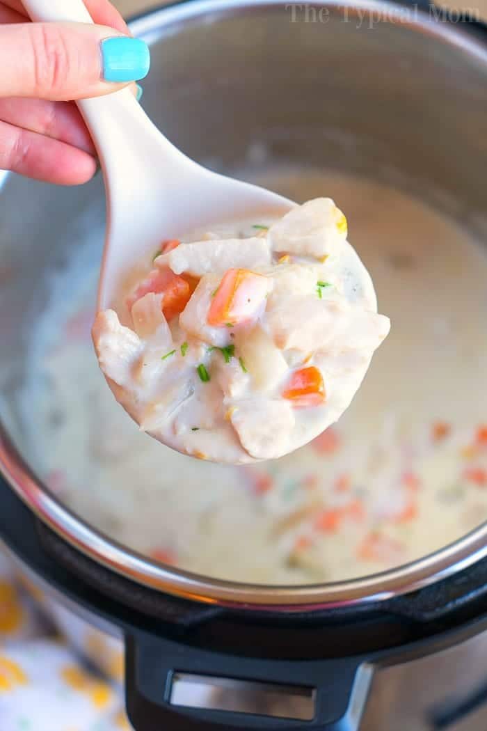 A spoonful of creamy chicken pot pie soup with vegetables, simmering perfectly in an Instant Pot.
