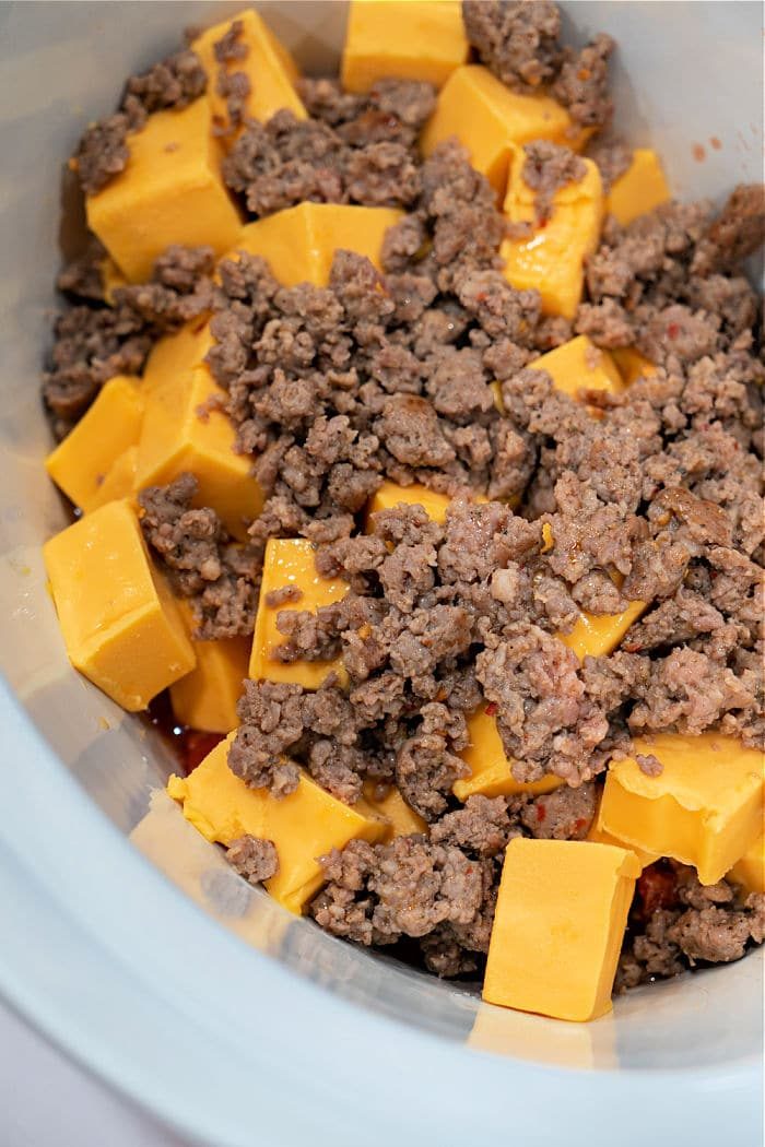 A crockpot brimming with chunks of Velveeta and crumbled cooked ground sausage, complemented by Rotel for an irresistible dip.