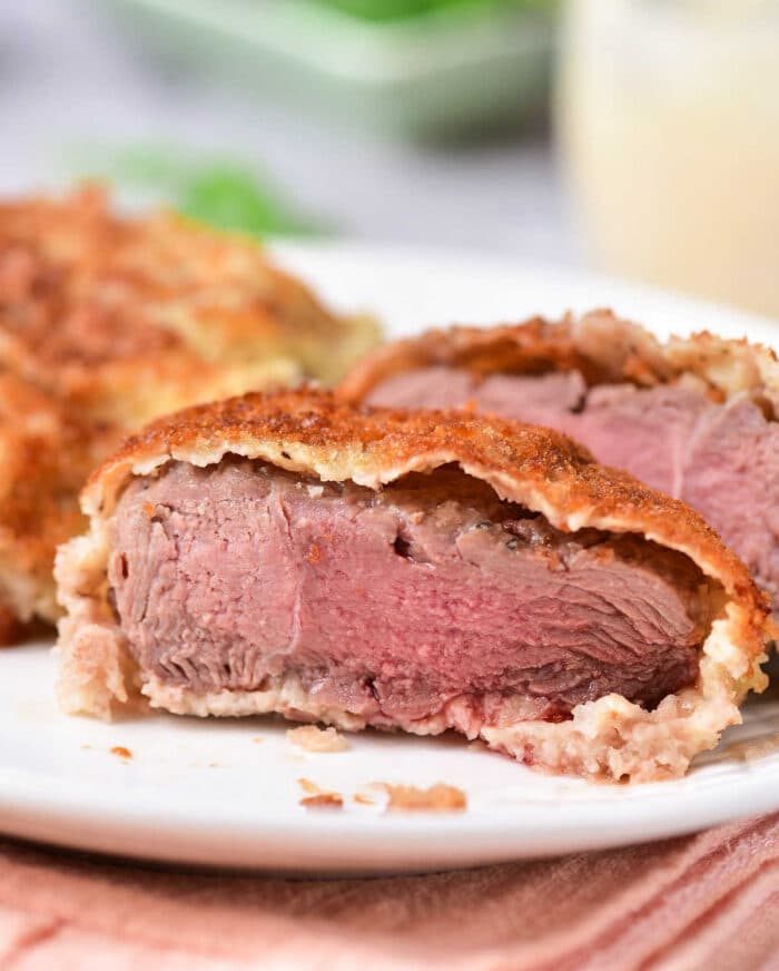 Close-up of a sliced venison cube steak, revealing tender pink wrapped in flaky pastry