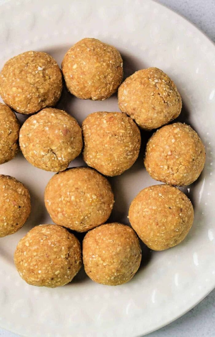 Twelve round, golden-brown matzo balls, artfully arranged on a white, textured plate.