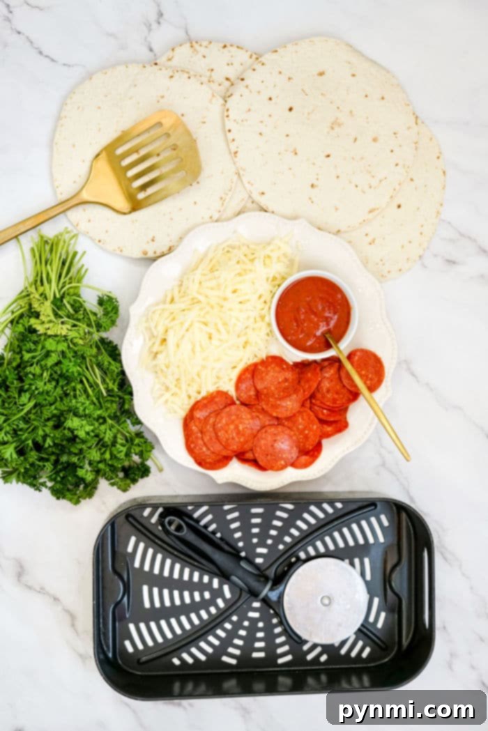 Crispy Air Fryer Tortilla Pizza 3 Air Fryer Tortilla Pizza essentials: tortillas, shredded cheese, pepperoni, sauce, parsley, spatula, pizza cutter, and an air fryer basket arranged on the counter, perfectly showcasing all the simple ingredients required for this quick and easy recipe.
