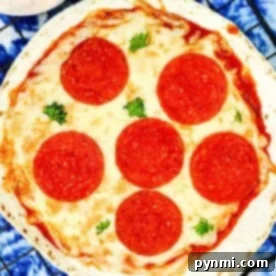 A perfectly cooked Air Fryer Tortilla Pizza, generously topped with melted cheese and six slices of pepperoni, garnished with fresh parsley, sitting on a wire rack next to a pizza cutter.
