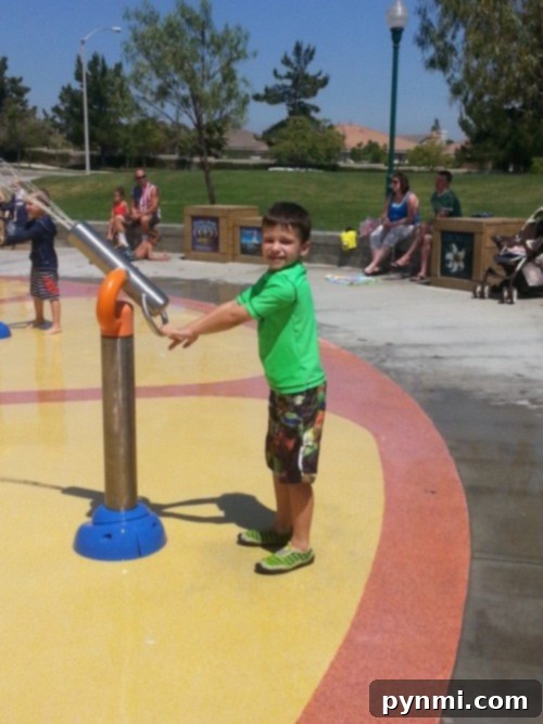 Children playing under a large water arch at a splash pad in Corona, California