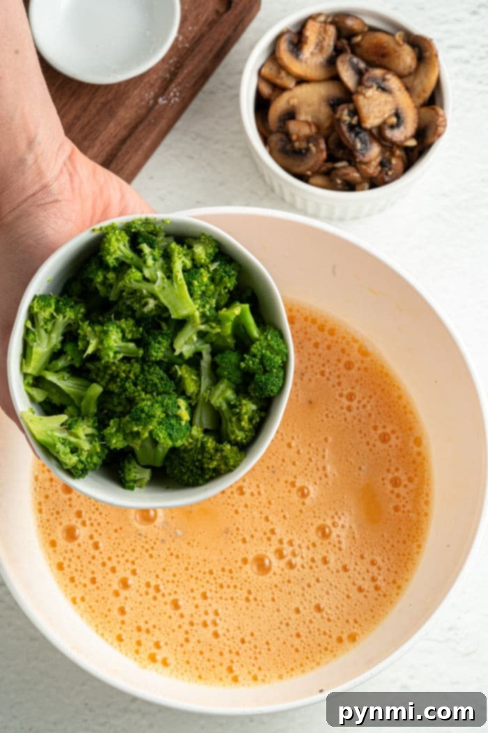 Side view of a muffin tin filled with freshly baked broccoli quiche