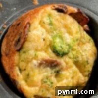 Close-up of a savory, crustless broccoli quiche muffin with mushrooms nestled in a muffin tin.
