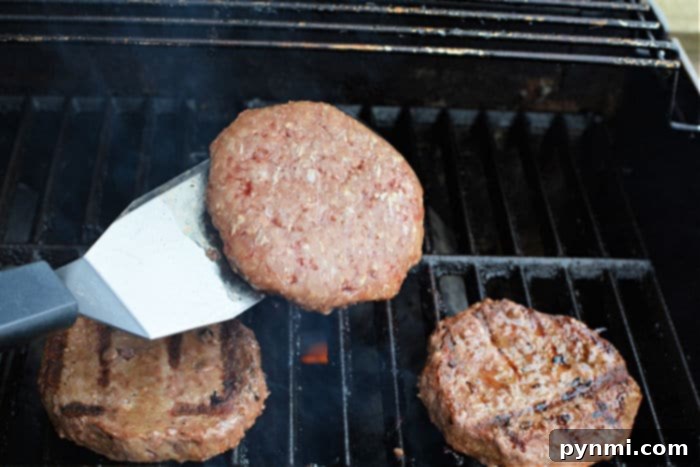 Grill Frozen Burgers to Perfection 5 Close-up of several frozen burger patties cooking on a hot grill