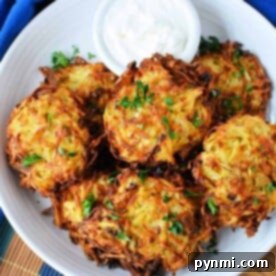 Plate of crispy air fryer latkes garnished with parsley, served with a small bowl of sour cream on a wooden table.
