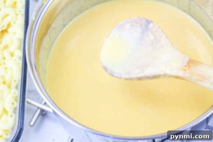 A close-up shot of the rich, creamy cheese sauce in a saucepan, being stirred, ready to be poured over macaroni for the Chick Fil A Mac and Cheese.
