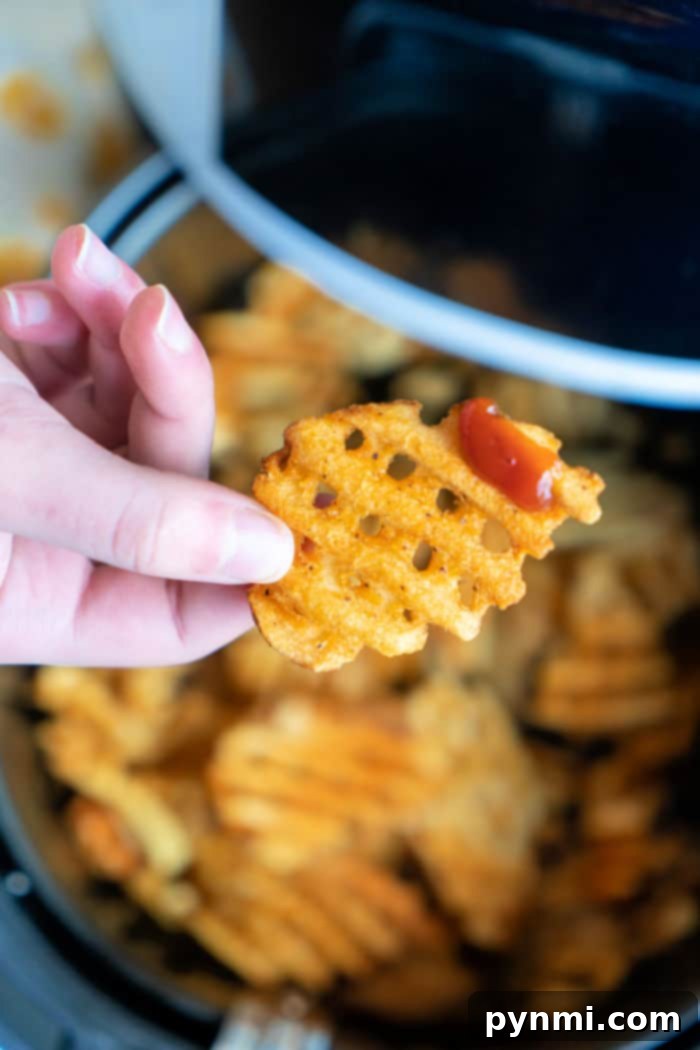 A vibrant display of crispy waffle fries, fresh from the air fryer, awaiting enjoyment.