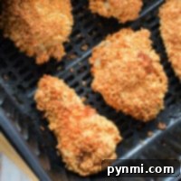 Four pieces of crispy, golden-brown gluten-free chicken are arranged in an air fryer basket. The chicken appears evenly cooked and crunchy.