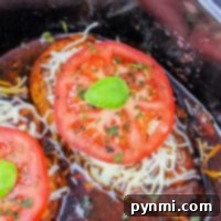 Crockpot chicken made with frozen breasts, melted cheese, sliced tomatoes, and herbs offers a convenient and delicious meal from your slow cooker.