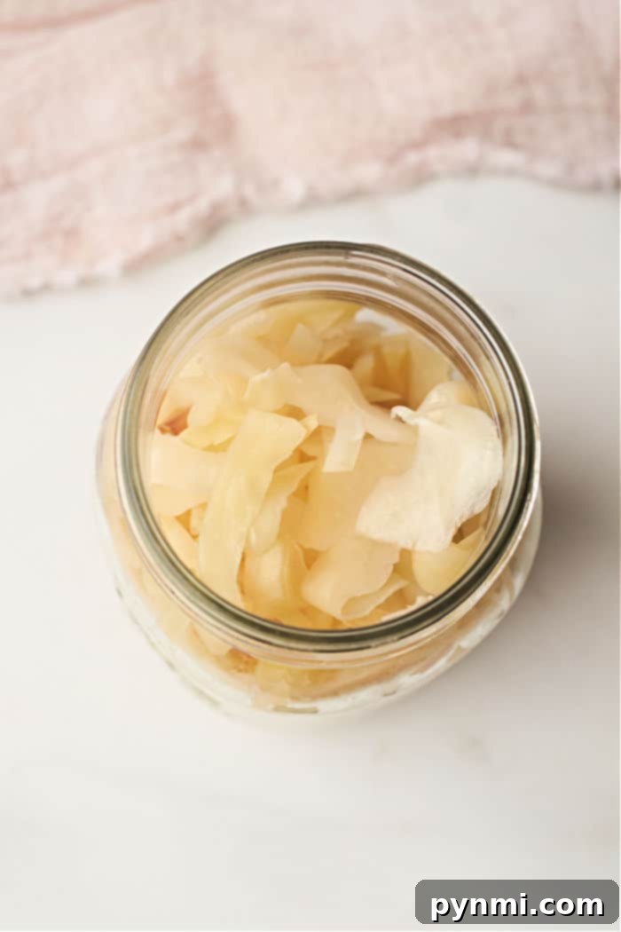 A glass jar filled with marinated cabbage rests on a light fabric background, reminiscent of the subtle simplicity of a quick sauerkraut recipe.