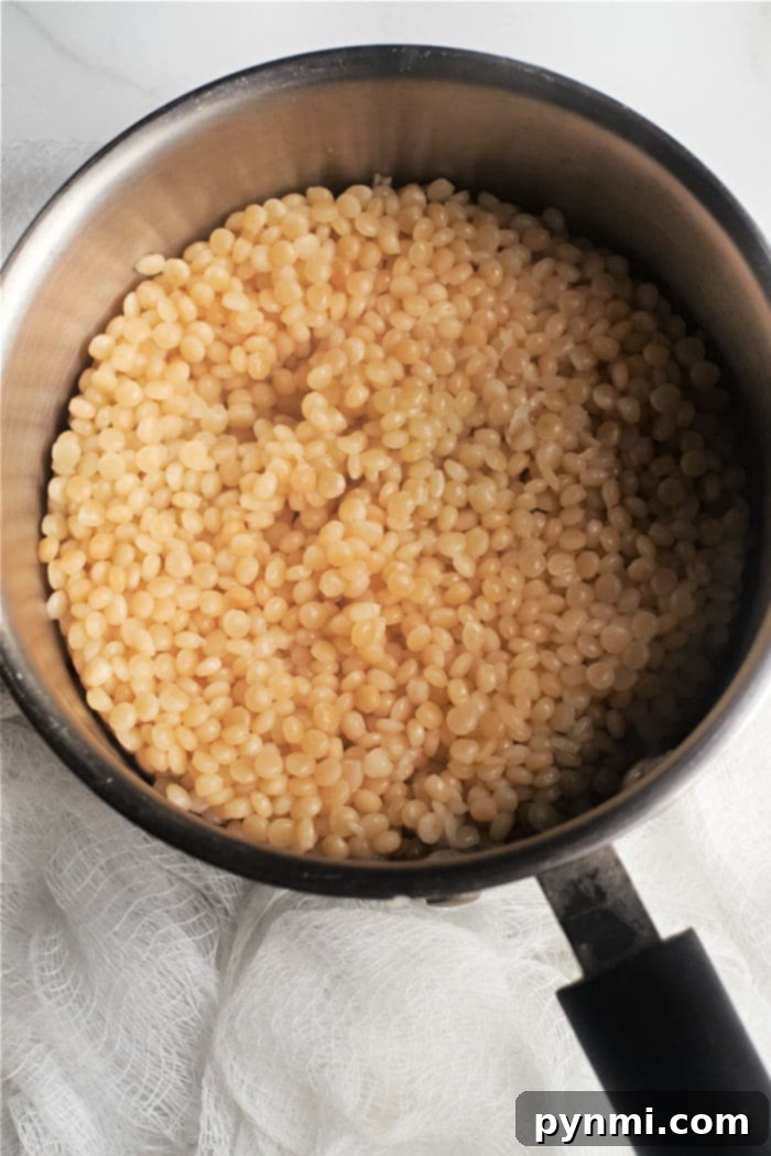 Perfect Pearl Couscous Every Time 4 Cooked pearl couscous in a saucepan, demonstrating the fluffy texture after preparation.