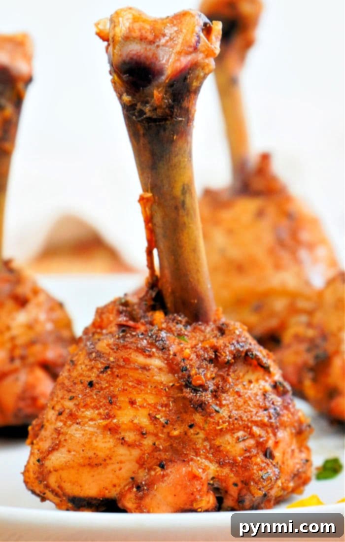 Perfect Lollipop Chicken Drumsticks 5 A close-up shot of perfectly cooked lollipop chicken drumsticks, golden brown and glistening, resting on a serving dish.