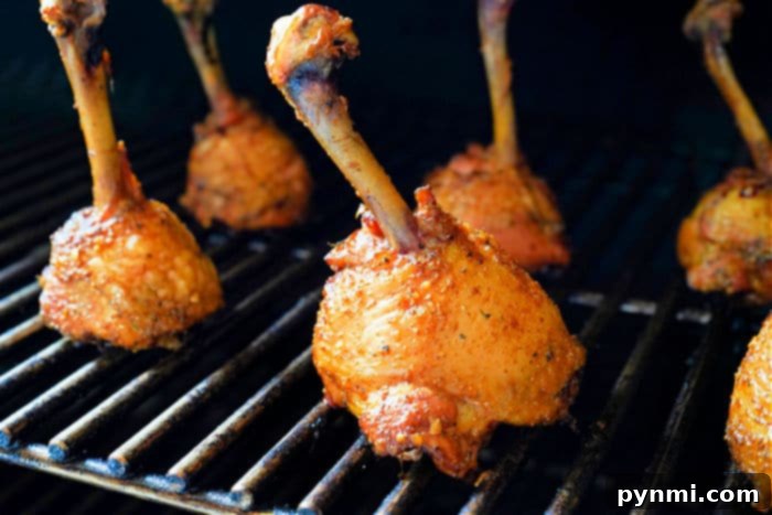 Perfect Lollipop Chicken Drumsticks 6 Grilled lollipop chicken legs with a smoky char, perfectly arranged on a barbecue grill.