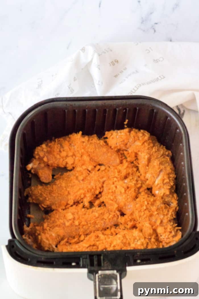 Cheese It Chicken Tenders in an air fryer basket, perfectly cooked and golden brown.