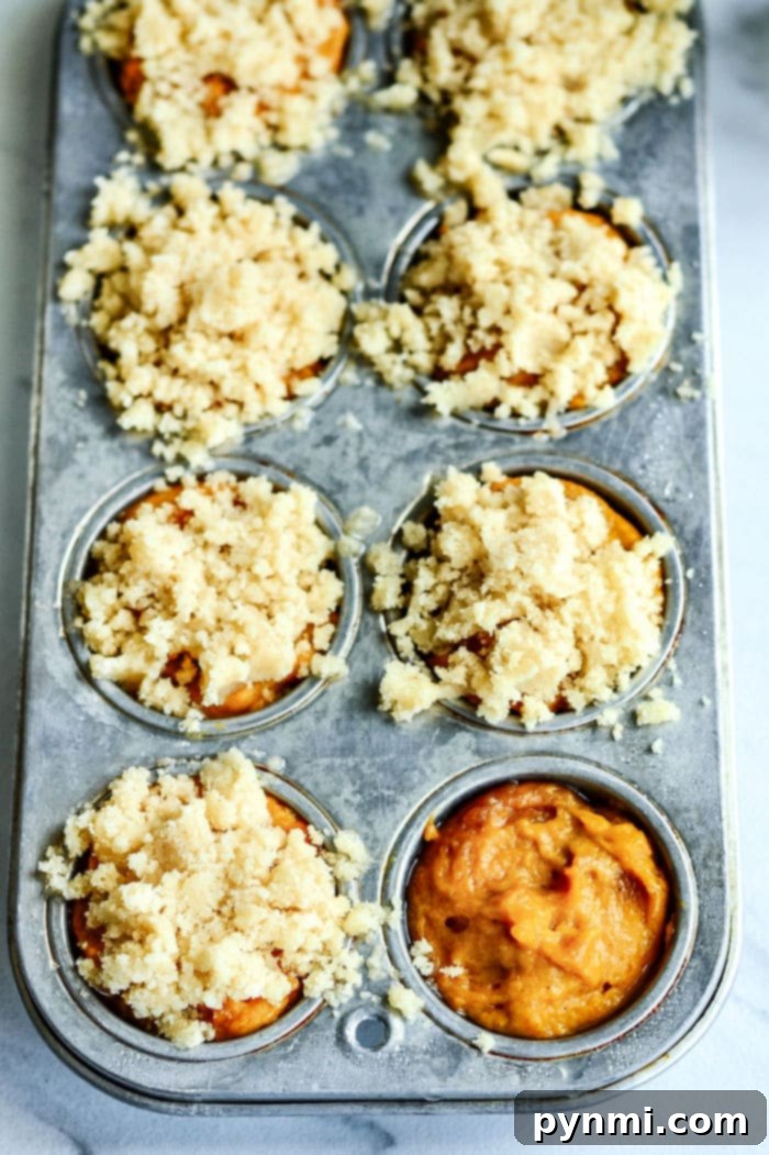 Mini Pumpkin Chocolate Chip Muffins in a basket, with a scattering of chocolate chips around them.