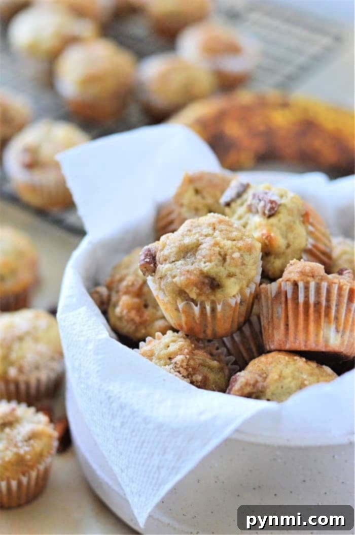 A white bowl filled with freshly baked mini muffins, lined with a napkin, rests invitingly on the table.