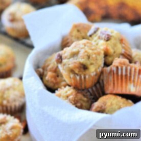 Golden Banana Bites 5 A bowl of mini banana nut muffins lined with a white napkin, with more delicious mini banana muffins and ripe bananas in the background.