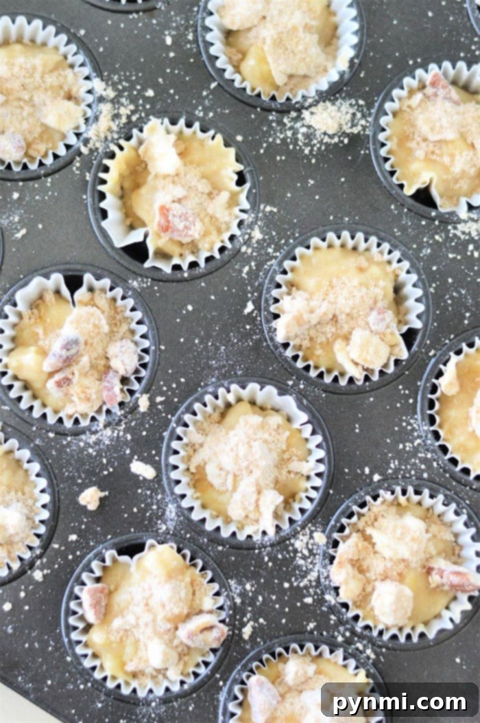 A close-up of an empty mini muffin tin with several paper liners in place, ready for batter.