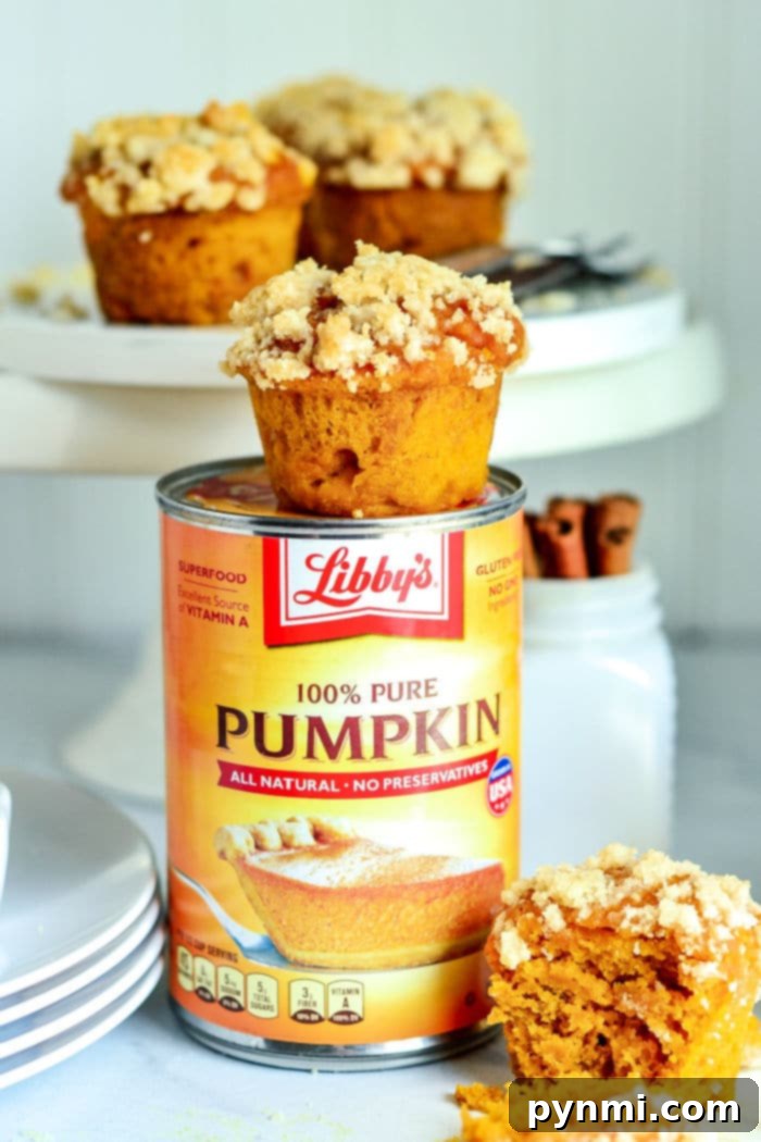 A festive arrangement of Libby's Pumpkin Muffins on a white stand, garnished with fall leaves and a small pumpkin, highlighting their appeal.