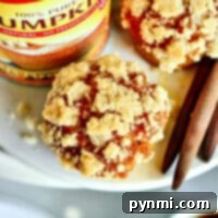 Close-up of a crumbly Libby's Pumpkin Muffin with a pumpkin can and cinnamon sticks artfully arranged on a plate.