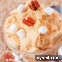 Pumpkin cream cheese mousse topped with marshmallows and pecans in a glass dish.