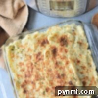 Creamy mashed potato casserole reminiscent of an Instant Pot Shepherd's Pie, served in a glass dish next to your trusty instant pot and a kitchen towel.
