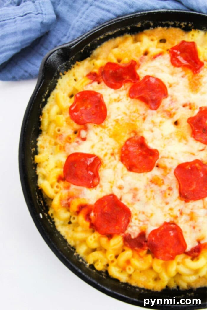 Irresistible Pizza Mac and Cheese in a cast iron skillet, topped generously with pepperoni and melted cheese, ready to be served