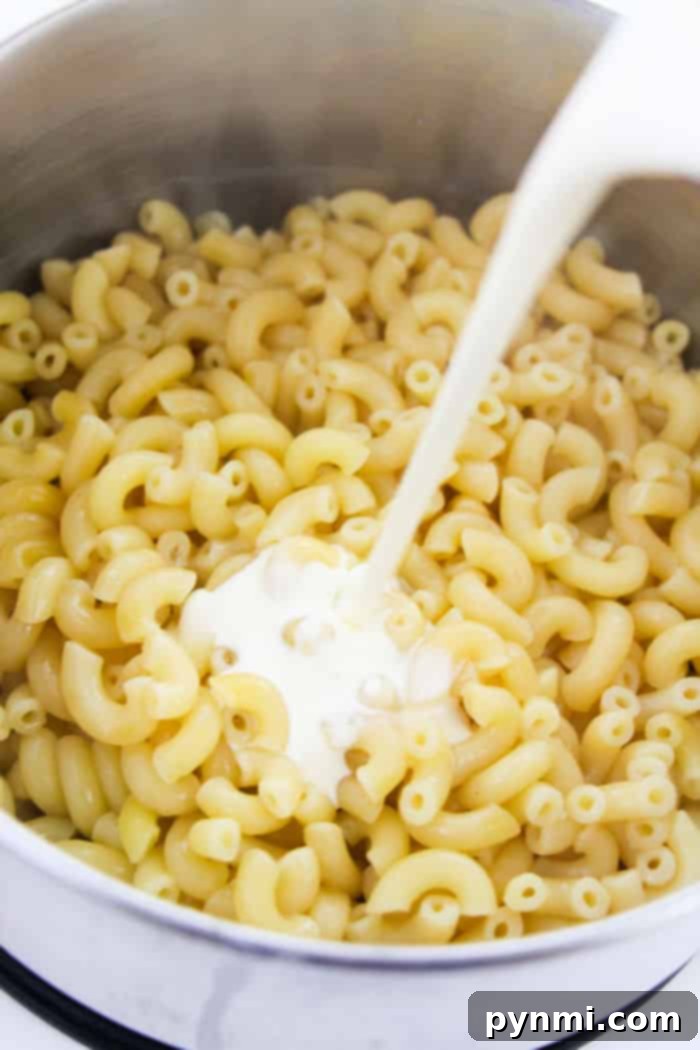 Close-up of creamy, golden mac and cheese, ready for pizza toppings, showcasing its rich texture
