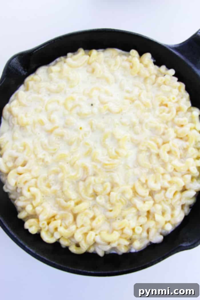 Golden, bubbling cast iron macaroni and cheese, freshly baked and ready to be topped with pizza ingredients