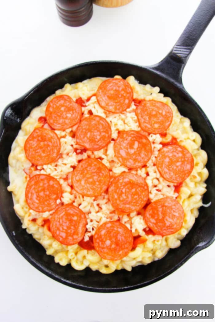 A vibrant close-up of Pepperoni Mac and Cheese in a skillet, showcasing melted cheese and perfectly placed pepperoni slices
