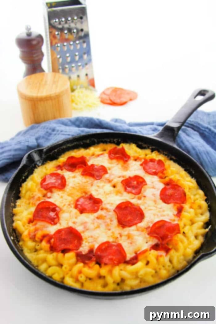 A large, appetizing serving of Pizza Macaroni and Cheese, brimming with toppings and gooey cheese, ready to be devoured