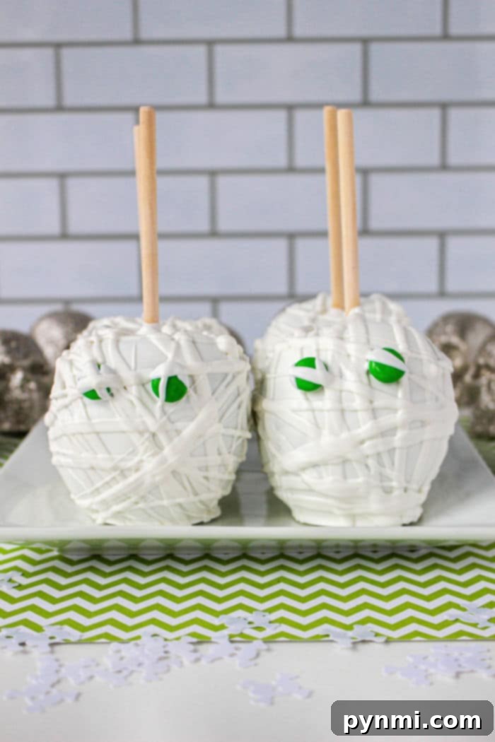 Ghostly White Chocolate Candy Apples 6 A plate of white chocolate mummy apples, ready for Halloween, with a festive napkin.
