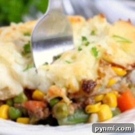 A fork digs into the savory vegetable shepherd's pie, perfectly slow-cooked in a crockpot and topped with creamy mashed potatoes and melted cheese.
