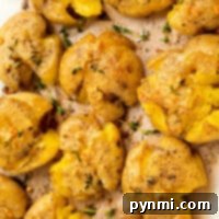 Crispy smashed potatoes with herbs and seasoning on a baking tray, perfectly crafted using an air fryer.