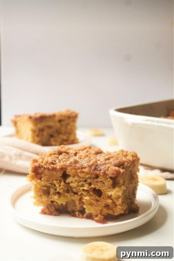 Ultimate Banana Streusel Coffee Cake 10 An entire banana bread coffee cake in a white ceramic dish, covered in streusel.