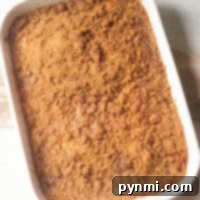 A white baking dish holds a freshly baked banana coffee cake with a crumb topping, resting invitingly on a light countertop.