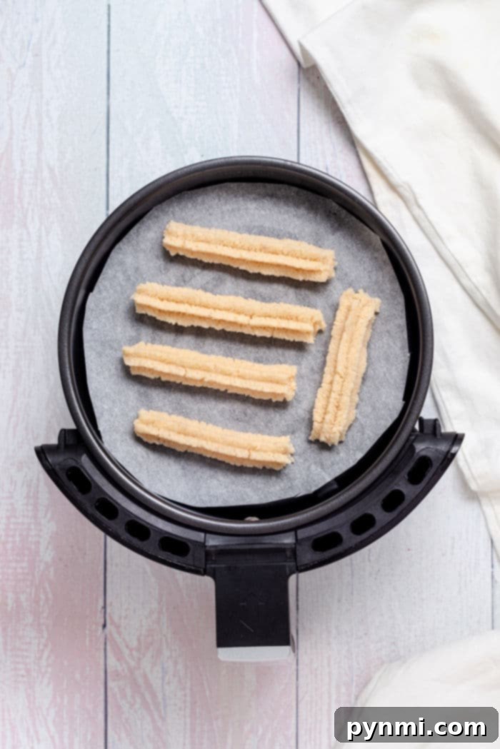A plate of freshly air-fried churros, golden and crispy, filled with rich chocolate.