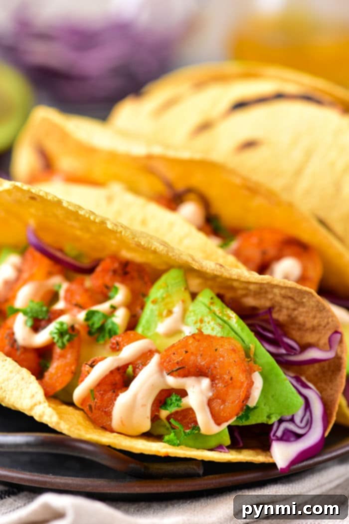 Easy Shrimp Tacos Recipe with Coleslaw - Two beautifully assembled shrimp tacos with coleslaw, avocado, and sauce.