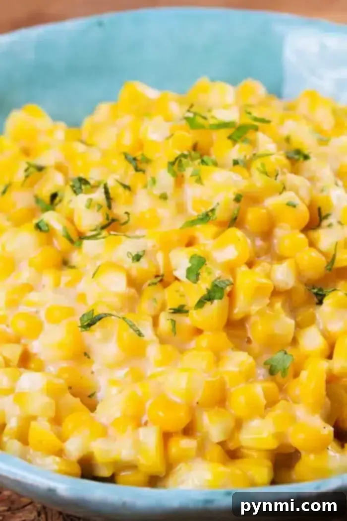 Golden Honey Butter Skillet Corn 2 A blue bowl brims with creamy Honey Butter Skillet Corn, topped with chopped green herbs. The dish looks indulgent and richly garnished, hinting at a luscious sauce or dressing that enhances its flavor.