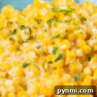Close-up of Honey Butter Skillet Corn, creamy and garnished with chopped parsley, elegantly served in a turquoise bowl.