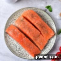 Three raw sockeye salmon fillets rest on a plate with spices, surrounded by cream, mushrooms, cherry tomatoes, and herbs—perfect for learning how to cook sockeye salmon with the finest accompaniments.