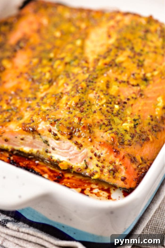 Sweet and Tangy Honey Mustard Salmon 5 Baked salmon fillet topped with a mustard sauce and herb crust in a rectangular dish.
