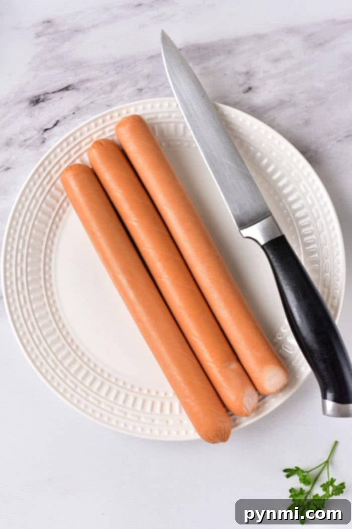 Three hot dogs and a knife rest on a white plate, garnished with parsley. Wondering how long to cook hot dogs in the microwave for that perfect texture and taste?