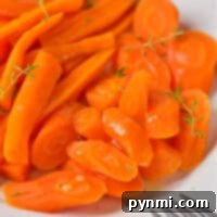 Effortless Microwave Carrots 6 A plate of sliced and whole cooked carrots, perfectly tender from the microwave, is garnished with fresh herbs, with a fork on the side.