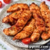 Savor the delicious chicken tenders on a plate, perfectly paired with cherry tomatoes and fresh herbs. For a quick alternative, try using frozen chicken tenderloins in the air fryer for equally tasty results.