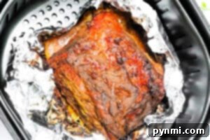 Air Fried Corned Beef Perfection 8 Air Fryer Corned Beef rests on aluminum foil inside the air fryer basket, freshly cooked and ready to serve.