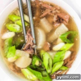 A bowl of Korean Oxtail Soup with green onions and tender meat, paired with chopsticks.