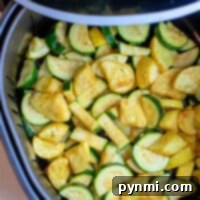 Air Fryer Squash and Zucchini perfectly illustrate the blend of convenience and taste, with sliced zucchini and squash arranged in an air fryer basket for a quick, healthy treat.